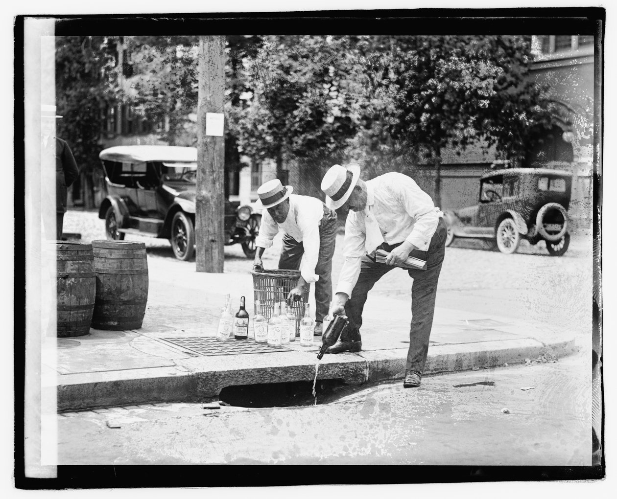 Zwei Männer gießen Schnaps in einen Regenabfluss, 8. Juli 1921 von American Photographer