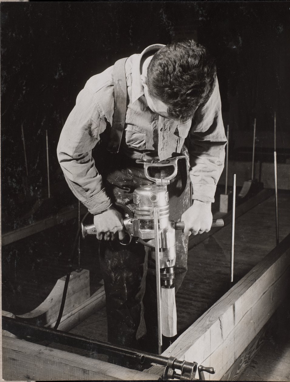 [Mann benutzt eine Handmaschine, um mit einem Stück Holz zu arbeiten] von Arnold Eagle