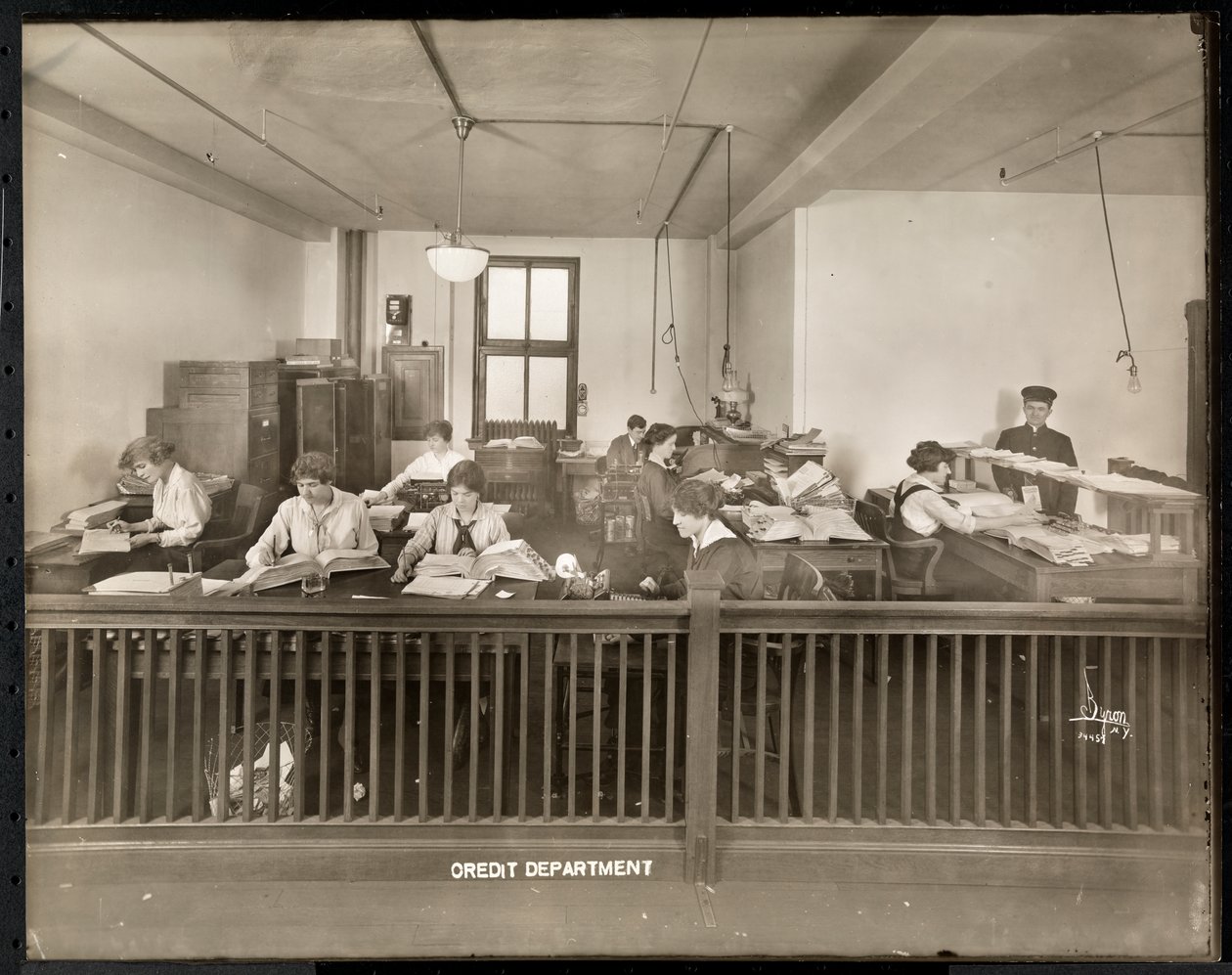 Ein Mann und eine Frau arbeiten im Kreditbüro der Mantle Lamp Co. of America, New York (1915-16) von Byron Company