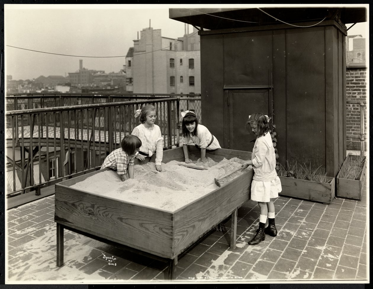 Blinde Mädchen spielen im Sandkasten auf dem Dach der New York Association for the Blind, 111 East 59th Street, New York, 1926 von Byron Company