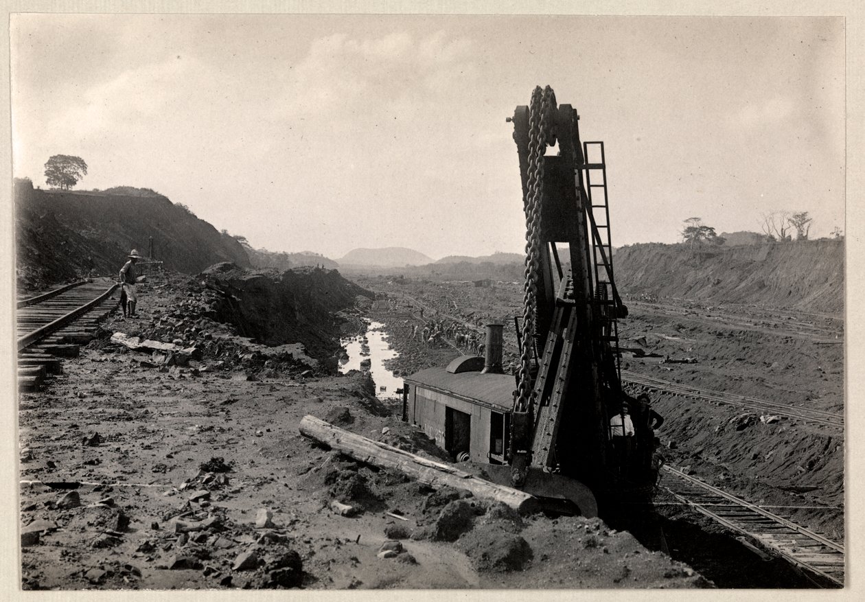 Ansicht von Arbeitern, die den Panamakanal graben, mit Eisenbahnschienen durch einen Graben und einer Art Grabmaschine im Vordergrund, 1912 oder 1913 von Byron Company