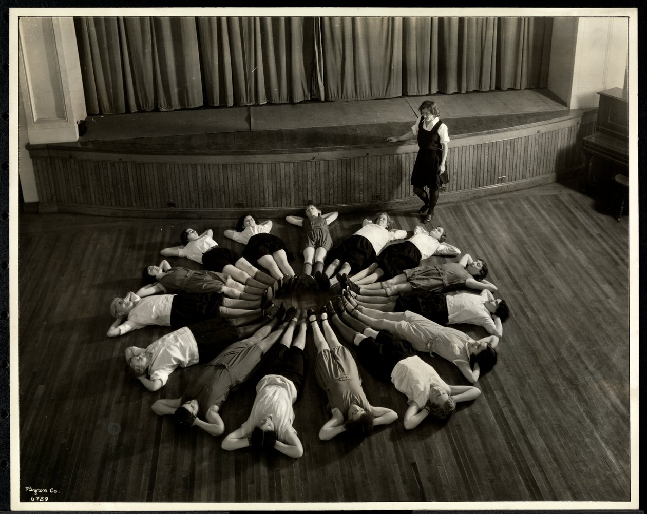 Junge blinde Frauen, die in einem Sternmuster auf dem Boden der Turnhalle der New York Association for the Blind, 111 East 59th Street, New York, 1933 liegen von Byron Company