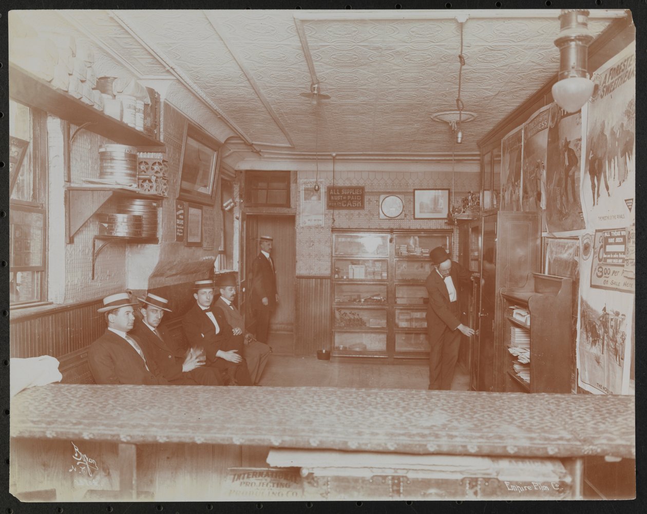 Empire Film Co (möglicherweise an der Broadway und 55th Street) mit Filmplakaten an der Wand und wartenden Kunden von Company Byron