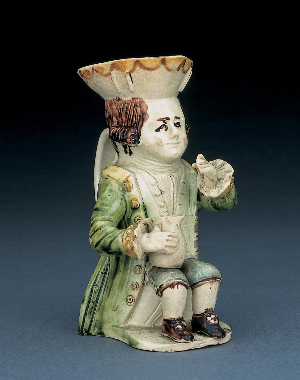 Trinker Toby Krug, sein Hut mit braunem und gelbem gewelltem Rand, sein eingeschnittenes braunes Haar en queue und mit einer weißen Rosette, sitzend mit einem Balusterkrug auf seinem Knie, ca. 1770 von English School