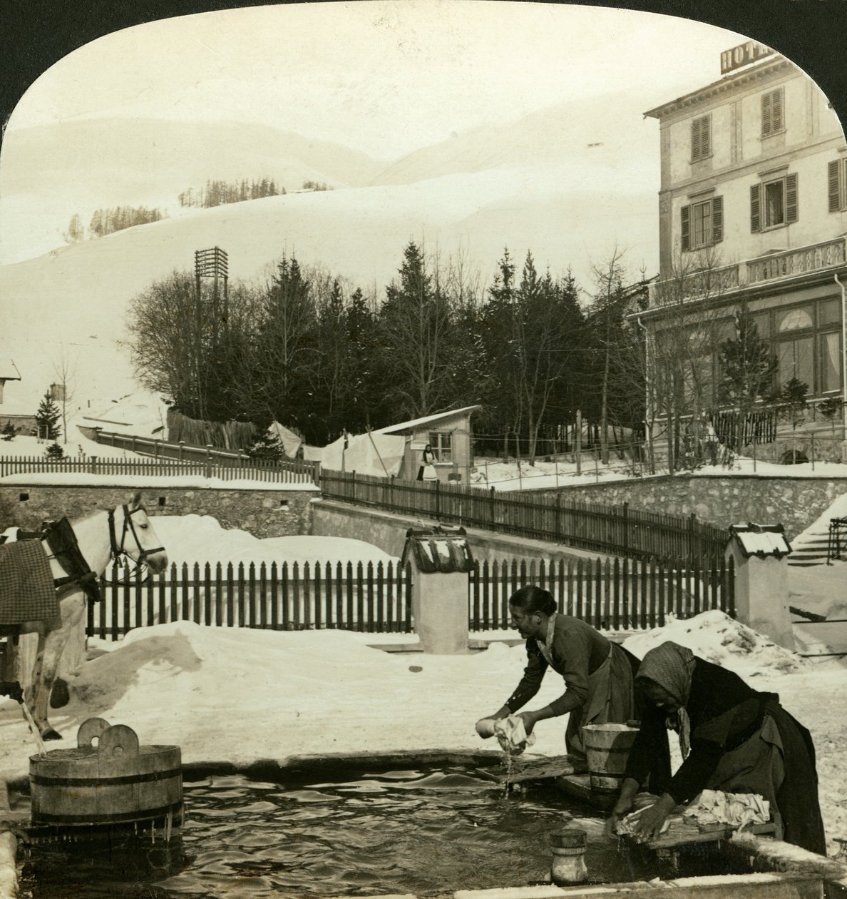 Frauen waschen Kleidung am öffentlichen Brunnen im tiefsten Winter, Zuoz, Schweiz von H. C. White