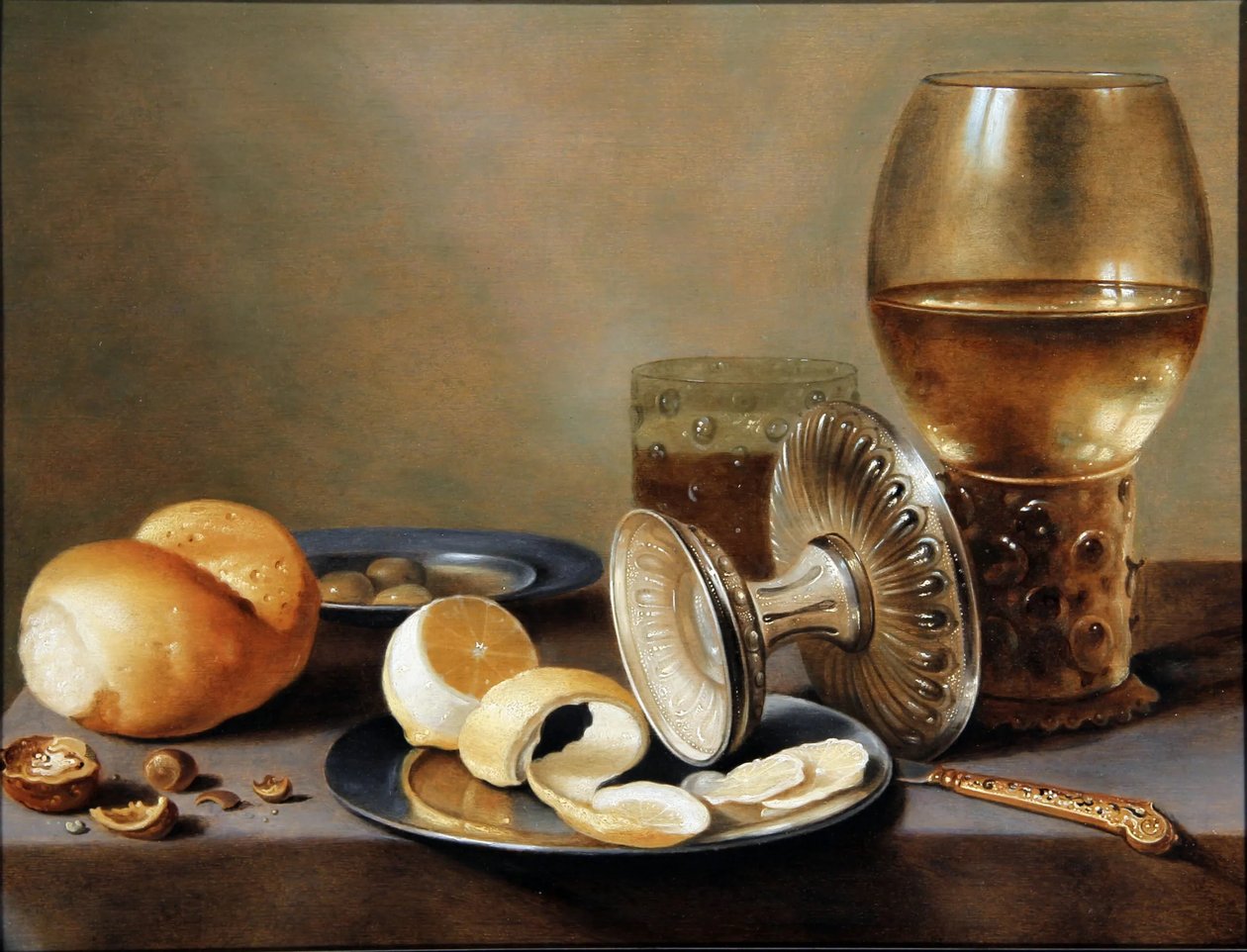 Monochromes Bankett mit zwei Zinngeschirren, einem umgestürzten silbernen Tazza, einem vergoldeten Messer, einem Glas mit Bier, einem Römer mit Wein, einem Brötchen, Nüssen, Oliven und einer halb geschälten Zitrone von Hans van Sant