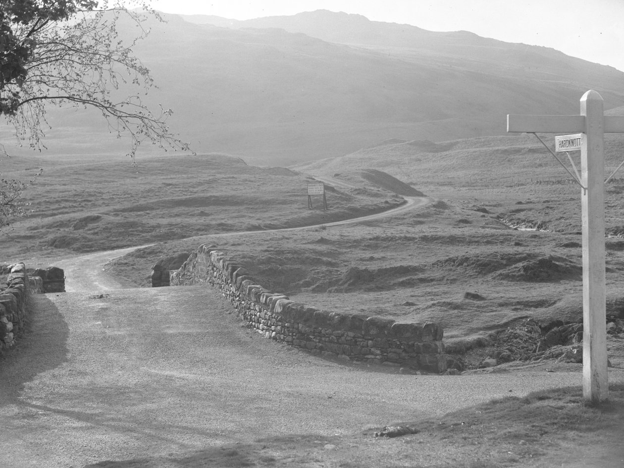 Blick auf die Straße über den Hardknott Pass mit einem Schild in Richtung Hardknott von Joseph Hardman