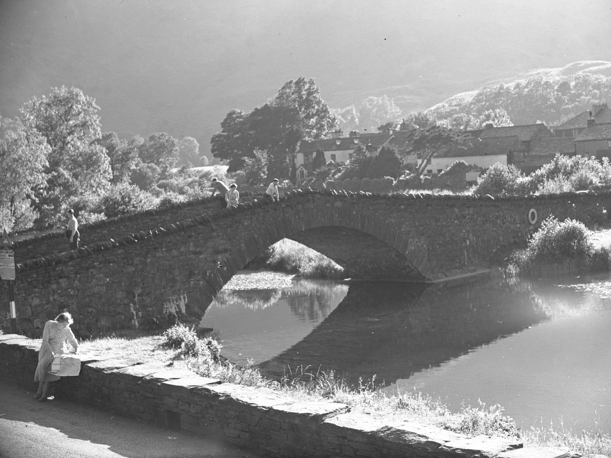 Frau sitzt auf einer Mauer und studiert eine Karte mit Fluss und Steinbrücke im Hintergrund von Joseph Hardman