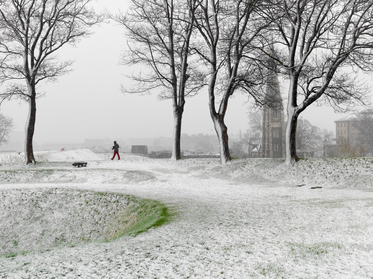 Einsame Figur, die während eines Schneesturms in der Festung Kopenhagen spaziert, Dänemark, 2022 (Foto) von Sisse Brimberg