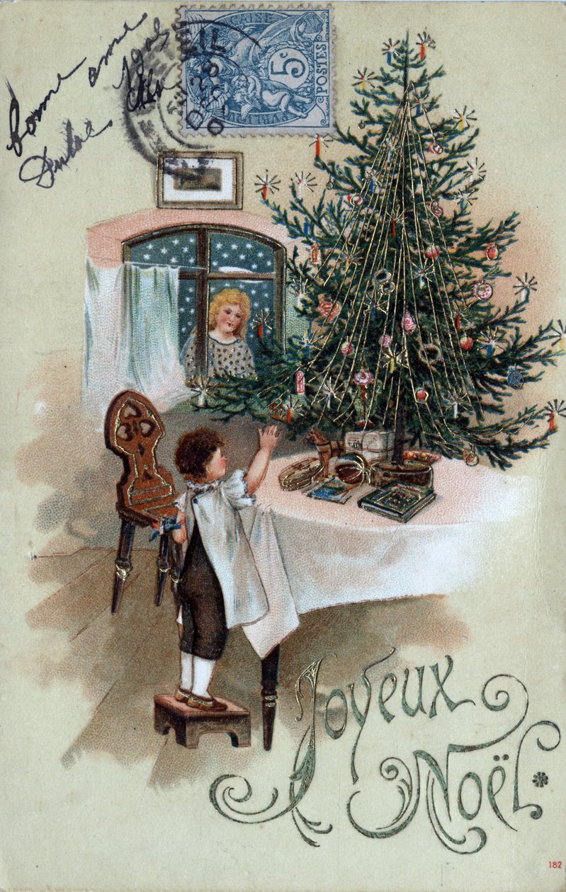 Weihnachtsgrußkarte: Ein Kind vor einem Weihnachtsbaum posiert auf einem Tisch, beobachtet von einem Engel im Fenster - Postkarte von 1905. von Unbekannt