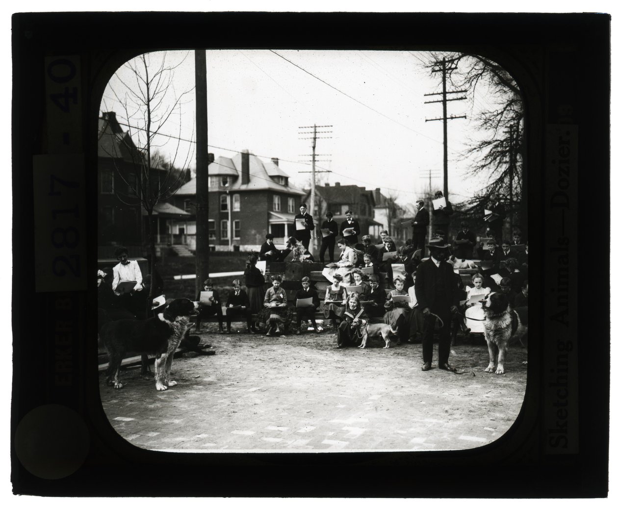 Horizontales, schwarz-weißes Foto von Schülern, die Hunde in einem Freiluftklassenzimmer zeichnen von Unknown