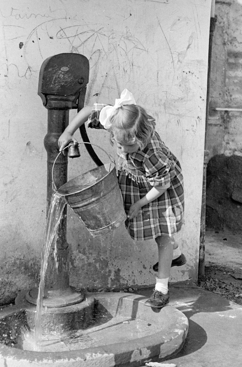 Kleines Mädchen leert einen Eimer Wasser in einen Pumpbrunnen, 9. Mai 1939 von Vincenzo Balocchi