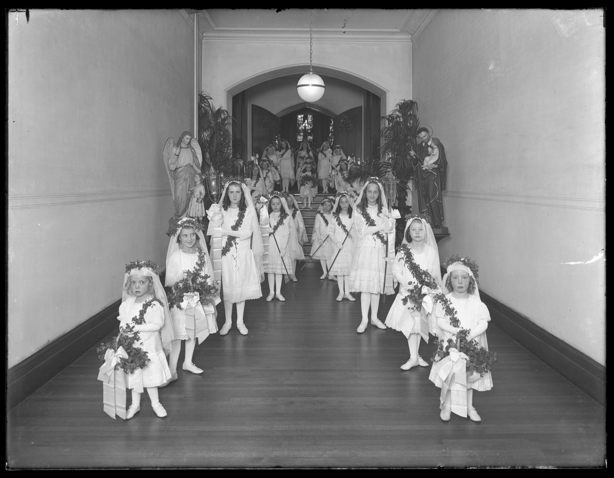 Kleine Mädchen im römisch-katholischen Waisenhaus, Kingsbridge, Bronx, kommen in weißen Kleidern mit Kränzen und Girlanden von der Kapelle zurück, 20. Oktober 1914 von William Davis Hassler