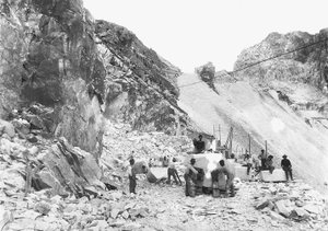 Ausgräber bei der Arbeit in einem Marmorbruch in den Apuanischen Alpen, Toskana. Einige von ihnen sitzen auf bereits quadratischen Marmorblöcken.