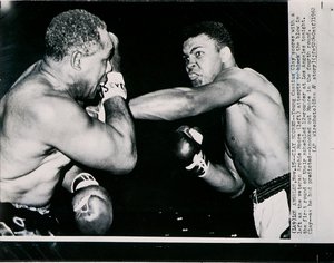 Der junge Cassius Clay trifft mit einem linken Haken gegen den Veteranen Archie Moore in der ersten Runde des Kampfes in Los Angeles von American Photographer