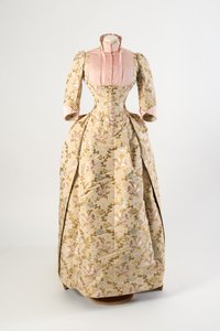 Kleid aus hellbrauner Seide mit einem Design aus mauve, blauen und gelben Blumen und grünen Blättern, hellrosa gerippte Seidenmieder und Manschetten
