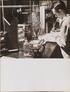 Mann im Labor benutzt beide Hände, um eine große Pipette in einen Becher zu setzen von Arnold Eagle