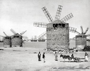 Windmühlen am Mittelmeer in Alexandria, Ägypten. Im Vordergrund posieren einige Ägypter mit einem kleinen Wagen