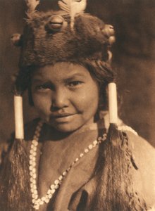 Nahaufnahme eines amerikanischen Indianerjungen des Klamath-Stammes oder -Dorfes. Er trägt einen Pelzhut mit aufgesetzten Eicheln und Federn und trägt sein Haar in zwei Zöpfen von Edward Sheriff Curtis