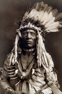 Wiesel Schwanz (Apohsuyis). Porträt des Indianerhäuptlings des Piegan-Stammes, trägt den berühmten Adlerfeder- und Wieselkopfschmuck, eine Wildledertunika, zwei Halsketten, eine aus Knochen und die andere aus Grizzlyklauen, und eine Tomahawk-Pfeife