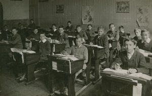 Männliche Schüler sitzen während einer Unterrichtsstunde an ihren Schreibtischen von English Photographer