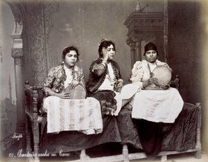 Porträt von drei jungen arabischen Sängerinnen in ethnischer Kleidung mit langen Halsketten. Sie posieren im Studio, sitzend. Zwei von ihnen halten ein Tamburin von Félix Bonfils