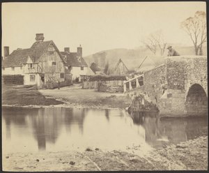 Ansicht eines Hauses über einen Fluss mit einer Brücke rechts