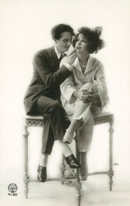 Androgyn Mann im Anzug, der Lippenstift auf die Lippen eines Mädchens im Pyjama aufträgt von French Photographer