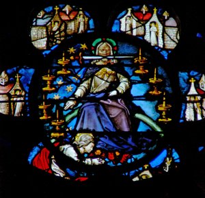 Das Westrosenfenster zeigt eine Szene aus dem Buch der Offenbarung: Christus auf einem Regenbogen thronend, umgeben von sieben goldenen Leuchtern und den sieben Kirchen Asiens. In seinem Mund ist das scharfe zweischneidige Schwert.