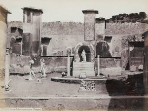 Teilansicht des erhöhten Gartens des Hauses des Marcus Lucretius in Pompeji, dekoriert mit Marmorstatuen und Hermen. In der Mitte ein Brunnen mit einer Nische. Im Hintergrund Fragmente von Wandmalereien