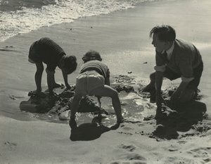 Drei Kinder spielen mit Sand am Strand