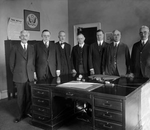 Federal Reserve Board, von links nach rechts: Sekretär Mellon; W.P.G. Harding; Vizegouverneur Edmund Platt; Charles S. Hamlin; Adolph Miller; Rechnungsprüfer D.R. Crissinger und J.R. Mitchell. Fotografie von Harris & Ewing, um 1905 / 1945.