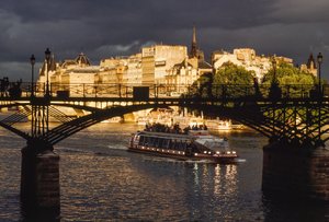 Dunkle Wolken ziehen auf, während ein Boot unter der Pont des Arts hindurchfährt. Seine, Paris...