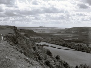 Eine Dame steht auf einem Hügel und blickt über die Landschaft bei Scout Scar von Joseph Hardman