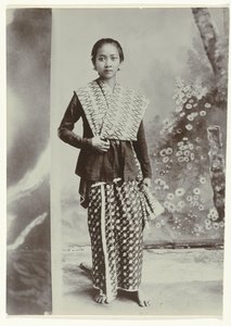 Studio-Porträt einer jungen javanischen Frau in einem Sarong mit Batikmuster und einem Hemd mit Karomuster von Kassian Cephas