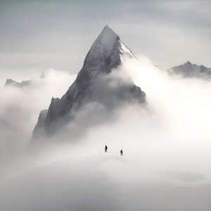 zwei Menschen beim Skifahren über einem wolkenverhangenen Berg