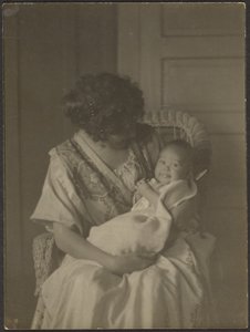 [Florence hält Baby im Schaukelstuhl]
