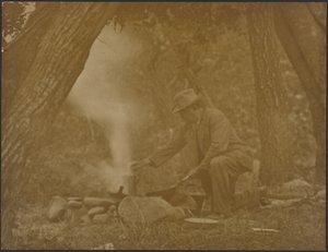[Mann kocht am Lagerfeuer im Wald] von Louis Fleckenstein