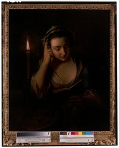 Ein junges Mädchen liest bei Kerzenlicht