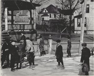 Eine Gruppe von Jungen in Wintermänteln steht auf einer unbekannten Straße entweder vor oder nach einem Schultag. von Unbekannt