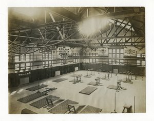 Horizontales Foto des Inneren einer großen Turnhalle. Geräte und Matten sind auf dem Boden verteilt