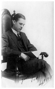 Mann sitzt auf einem Stuhl und liest ein Buch, 1918