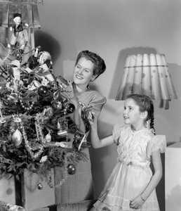 Frau und Mädchen schmücken einen Weihnachtsbaum, um 1948 von Unbekannt