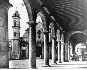 Ein Blick auf die alte Kathedralen-Plaza von Havanna, eingerahmt von den prächtigen Bögen eines angrenzenden Gebäudes, 1954 von Unbekannt Unbekannt