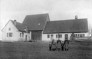 Bauernfamilie posiert vor dem Bauernhof.