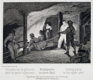 Salzmine: Besucher setzen sich in den oberen Teil der Rutsche, die in die unterirdischen Gänge der Mine führt, in Durrnberg, Österreich