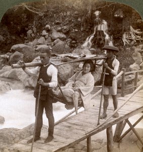 Japanische Frau in einem Yamakago-Bergstuhl überquert den reißenden Daiya-Fluss in der Nähe von Nikko, Japan von Underwood and Underwood
