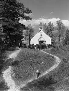 Männer versammeln sich vor einem kleinen ländlichen Gebäude, einer Schule oder einer Kirche mit Glockenturm