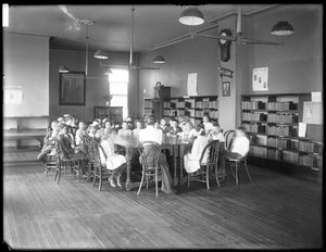 Kinder hören einer Frau im Lesesaal einer nicht identifizierten Filiale der Queens Borough Public Library zu, ca. 1910 von William Davis Hassler