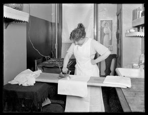 Unidentifizierte Frau, die die Verwendung eines elektrischen Bügeleisens demonstriert, ca. 1913-14 von William Davis Hassler